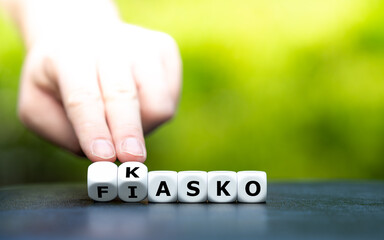Hand dreht Würfel und ändert den Ausdruck "Fiasko" in "Kasko".