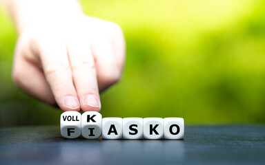 Hand dreht Würfel und ändert den Ausdruck "Fiasko" in "Vollkasko".