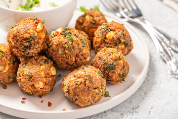 Homemade falafel close up. Chickpea balls with spices and yogurt with herbs on a gray concrete table.