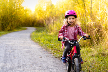 Fototapeta na wymiar happy cheerful child girl riding a bike in Park in the nature