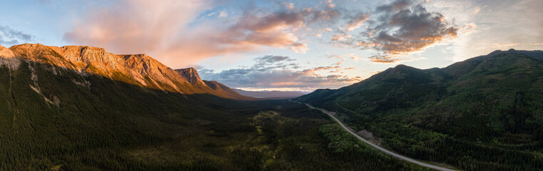 Picturesque Panoramic View of Scenic Highway surrounded by Golden Rocky Mountains at Sunset in Canadian Nature. Aerial Drone Shot. Alaska Highway, near Tagish, Southern Yukon, Canada.