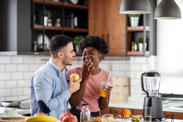 Multiethnic couple in the kitchen with smoothie and fruits on healthy morning breakfast
