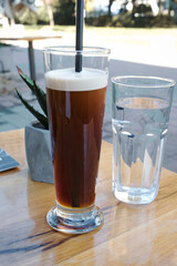 Glass of cold brew nitro coffee and toasted sandwich with ham, tomato and cheese for breakfast
