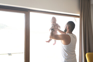 Father lifting up baby girl at home