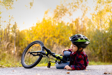 a little boy in a helmet fell from a Bicycle in the Park in the fall, sports injury