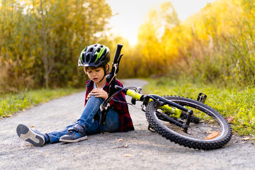 a little boy in a helmet fell from a Bicycle in the Park in the fall, sports injury