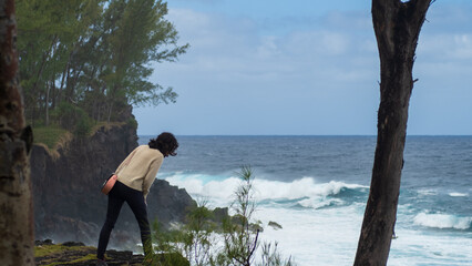 Girl standing annd looking down to the cliff and the stormy sea