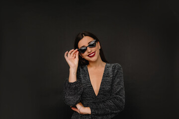 Charming stylish woman with red lips holding her glasses and looking at camera with smile