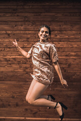 Ukrainian young woman jumping in a dress. Fashion summer 2021 style glamorous. Brown wooden striped background.