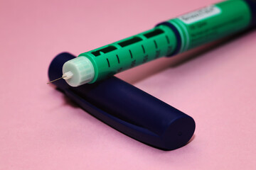 injector pen, insulin pen photographed close-up on pink background