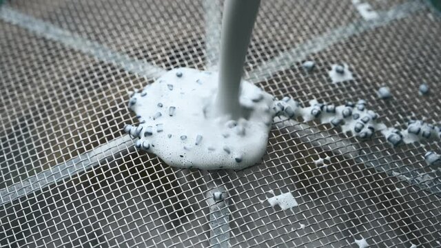 water rinse of final stage of rock tumbler over a metal screen.  