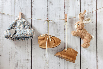 baby clothes on clothespins, small retro boots, soft toy rabbit, baby concept on a wooden...