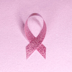pink glittering ribbon on pink glitter banner background. breast cancer awareness with copy space