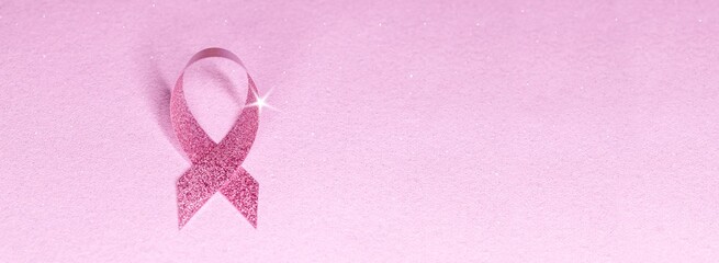 pink glittering ribbon with star shape on pink glitter banner background. breast cancer awareness symbol with copy space
