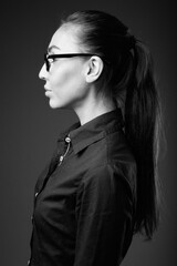 Studio shot of young beautiful businesswoman with eyeglasses in black and white