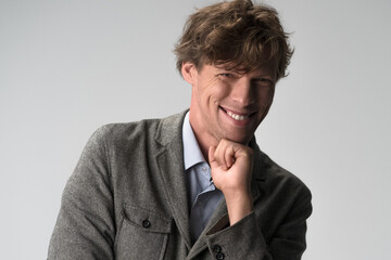 Handsome man rejoices and laughs with his chin on his fist. Studio portrait.