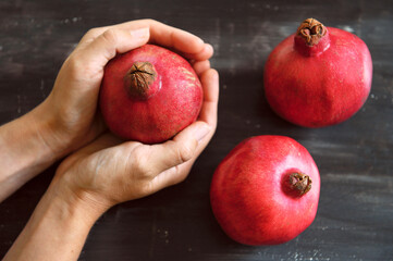 Ripe red pomegranates. Seasonal fruits. Royal fruit. Pomegranate in hands. Cutting a pomegranate. Selective focus.