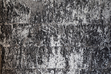 Abstract grunge background. White and black spotted tiled wall after fire. High quality photo.