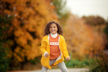 Cute afro girl smiling broadly outdoors and enjoying autumn day in park.