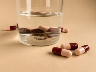 capsules with a glass of water, medicine on a beige background