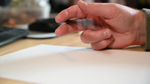 Nervously bouncing a pen on a pad of paper in a home office with a defocused mouse and keyboard in the background