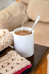Close-up of a white mug with hot chocolate, on a wooden table in a living room. Cozy winter concept at home. Vertical photography