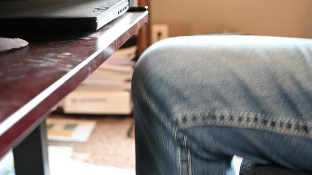 knee bouncing repeatedly as a person nervously waits while working in a home office