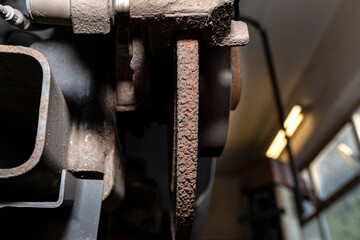 Old and damaged rear brake discs with caliper and brake pads in the car, on a car lift in a...