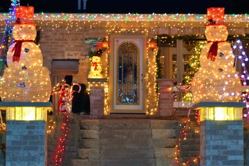 Christmas decoration: two snowmen flanking an illuminated staircase and surrounded by led lights at the entrance of an American house