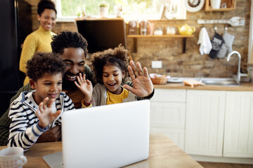 Happy black family making video call over laptop and waving to someone.