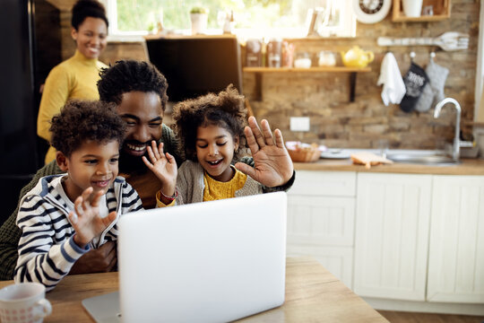 Happy black family making video call over laptop and waving to someone.