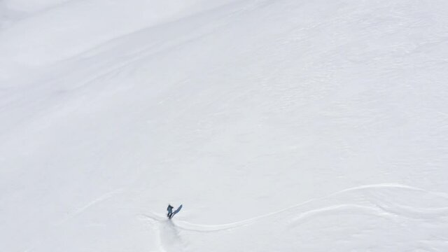 Aerial top view from drone snowboarder riding freeride on snowboard on snowy slope in winter mountain. Sportsman snowboarding on slope in forest. Extreme winter sport activity