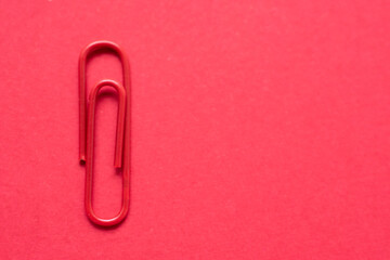 Red paper clip over a cherry red background, with copy space at the right side of the photo