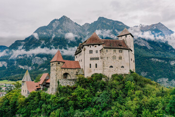 Fototapeta na wymiar Castle at Vaduz ancient stone building with mountain background and fog