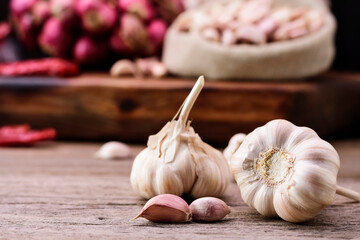 Garlic. Fresh garlic is placed on an old wooden table. Background with red onions and peppers