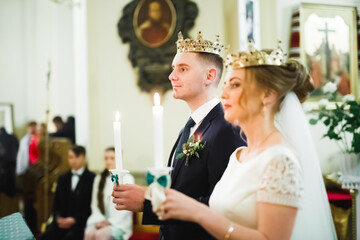 Bride and groom holding candles in church