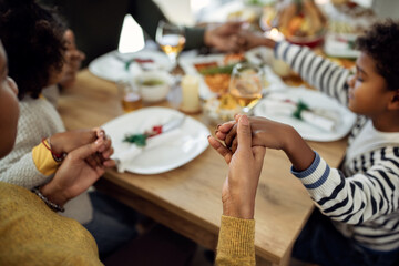Close-up of African American family saying grace before Christmas meal in dining room.