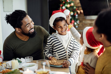 Happy black boy eating cookies and having fun with his family on Christmas.