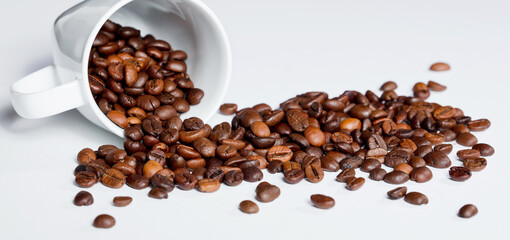 Isolated coffee beans (selective focus on coffee beans) with ceramic cup, white background.