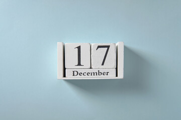 Wooden white calendar on blue background, date 17 December.