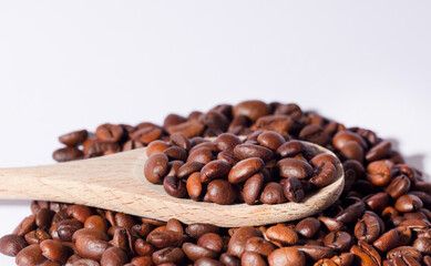 roasted coffee beans on wooden spoon, white background