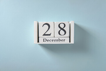 Wooden white calendar on blue background, date 28 December.