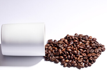 Isolated coffee beans (selective focus on coffee beans) with ceramic cup, white background.
