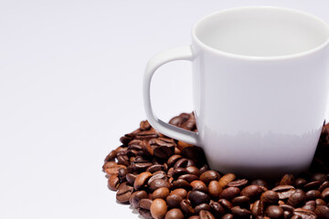 Isolated coffee beans (selective focus on coffee beans) with ceramic cup, white background.
