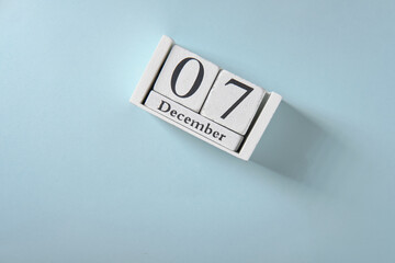 Wooden white calendar on blue background, date 7 December