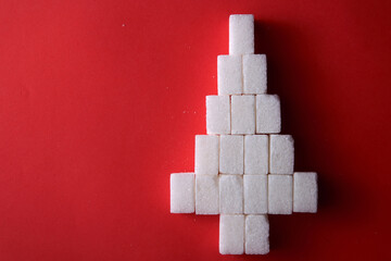 top view arranged of white sugar cube form christmas tree on red background