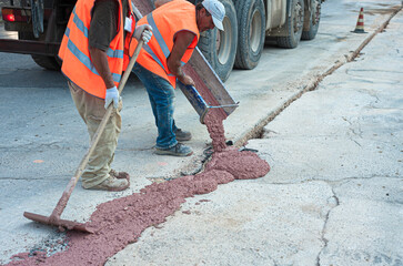 Concrete Mixing Truck and workers pouring concrete on street a winter afternoon