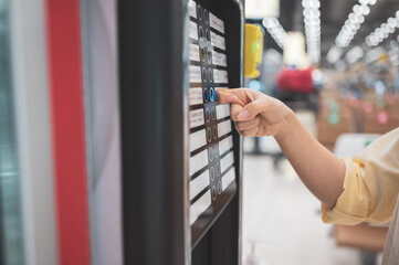 Asian woman buying can drink from vending machine in airport