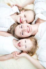 Obraz na płótnie Canvas Portrait of mom and her daughters smiling on the bed topview
