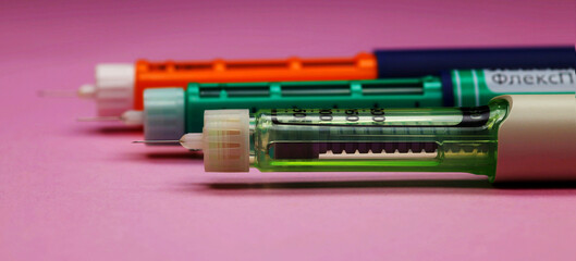 injector pen, insulin pens for hormone therapy of diabetics, photographed close-up on pink...